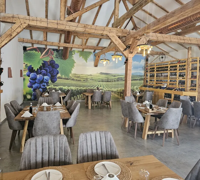 The dining room with oak tables, grey velvet chairs, wine shelves and a vineyard mural