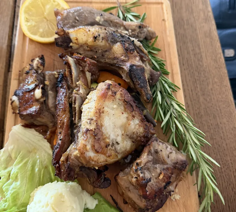 Grilled meats on a wooden board with rosemary, lemon and mashed potato