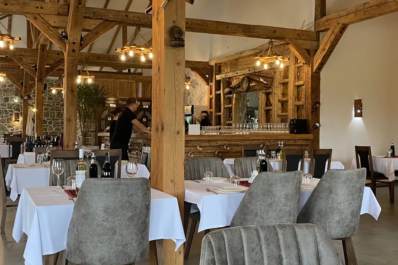 White-clothed tables and timber pillars in the restaurant, with the bar behind